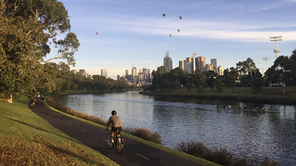 Cyclist on the Yarra River bike trail with the Melbourne skyline