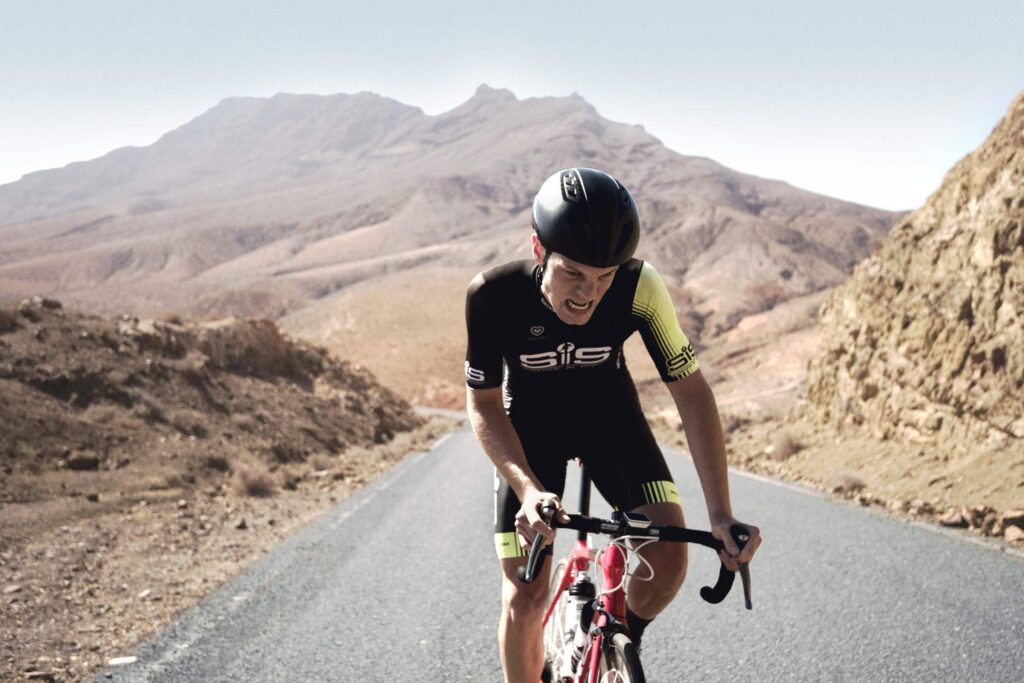 Road cyclist in SIS kit climbing a mountain road