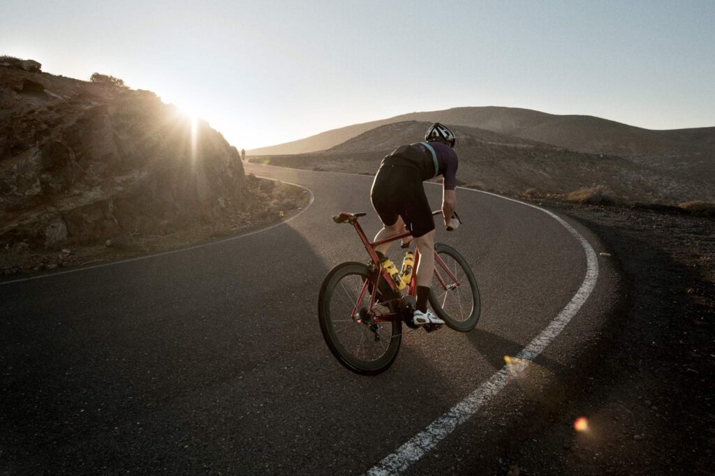 Road cyclist descending a mountain road at sunset